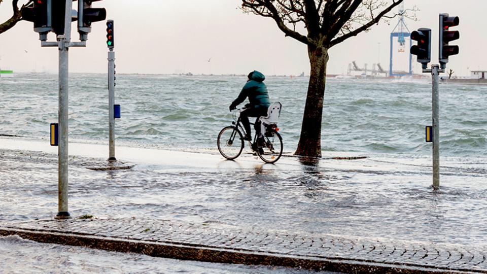 Person cyklar på vägen och det är översvämning